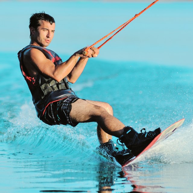 A person wakeboarding on a calm, blue lake.