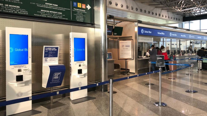 Просторная зона возврата налога в аэропорту с элегантными киосками с надписью «Global Blue» синего и белого цветов. 